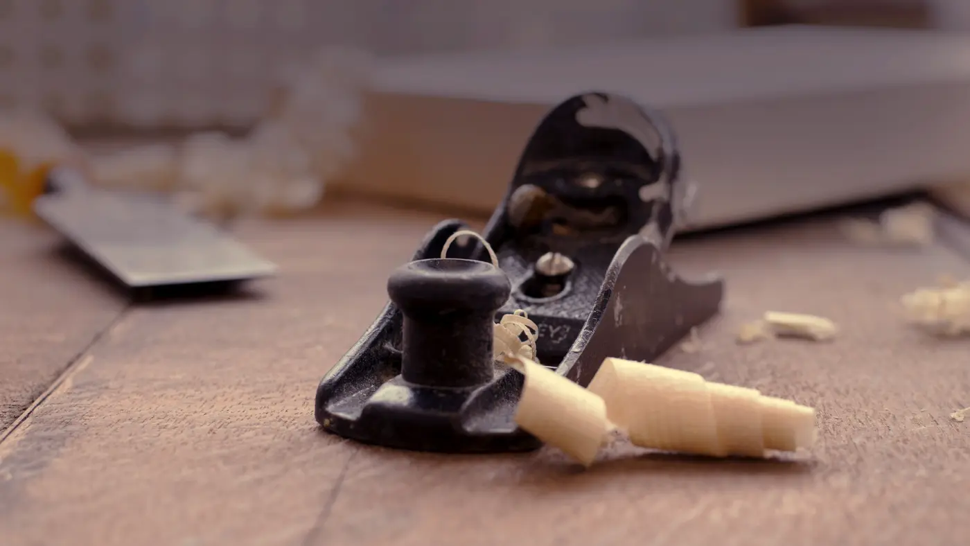 Woodworking hand plane with fresh shavings on a workbench