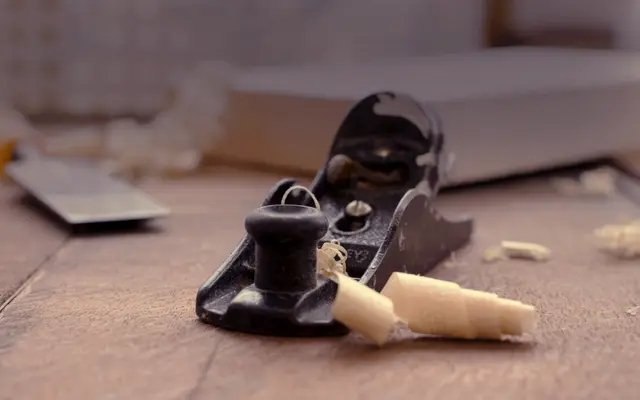Woodworking hand plane with fresh shavings on a workbench