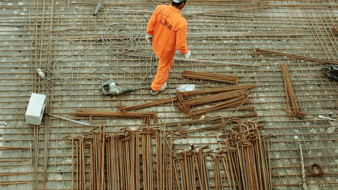 Worker in orange coveralls walking across rebar on a site