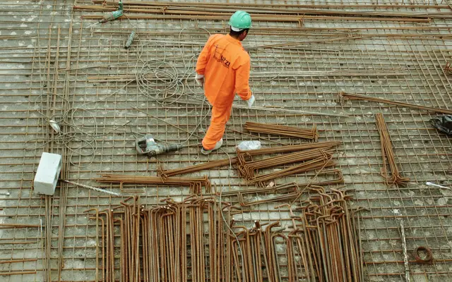 Worker in orange coveralls walking across rebar on a site