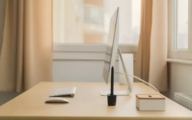 Minimal desk with a computer beside a curtained window