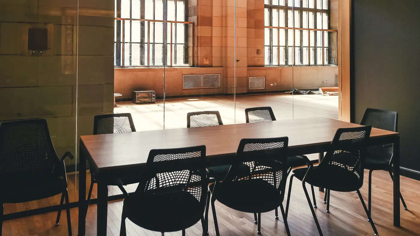 Loft boardroom with a dark table and large factory windows