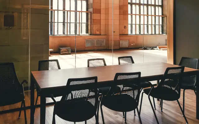 Loft boardroom with a dark table and large factory windows
