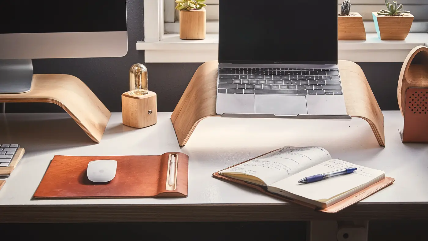 Tidy desk with laptop stand, leather mouse pad and open notebook