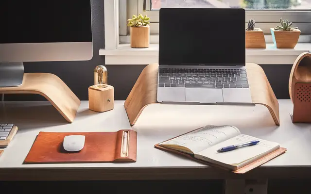 Tidy desk with laptop stand, leather mouse pad and open notebook