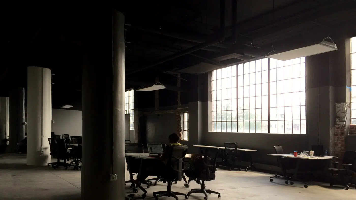 Open-plan loft office with desks, columns and tall windows