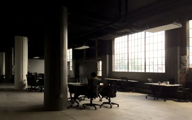 Open-plan loft office with desks, columns and tall windows