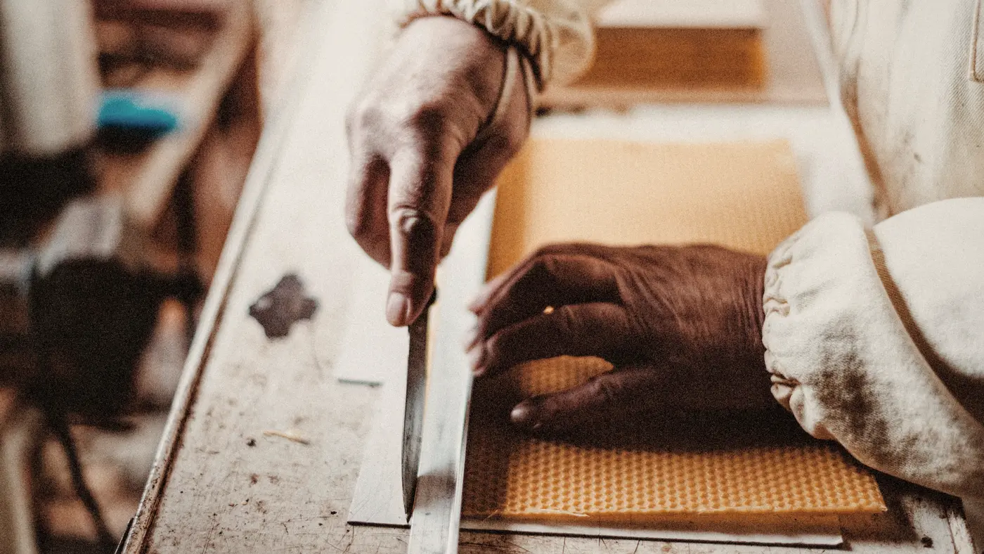 Craftsman's hands cutting material with a blade and steel ruler