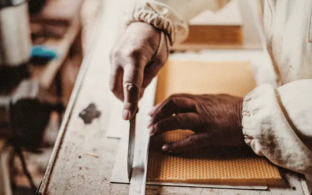 Craftsman's hands cutting material with a blade and steel ruler