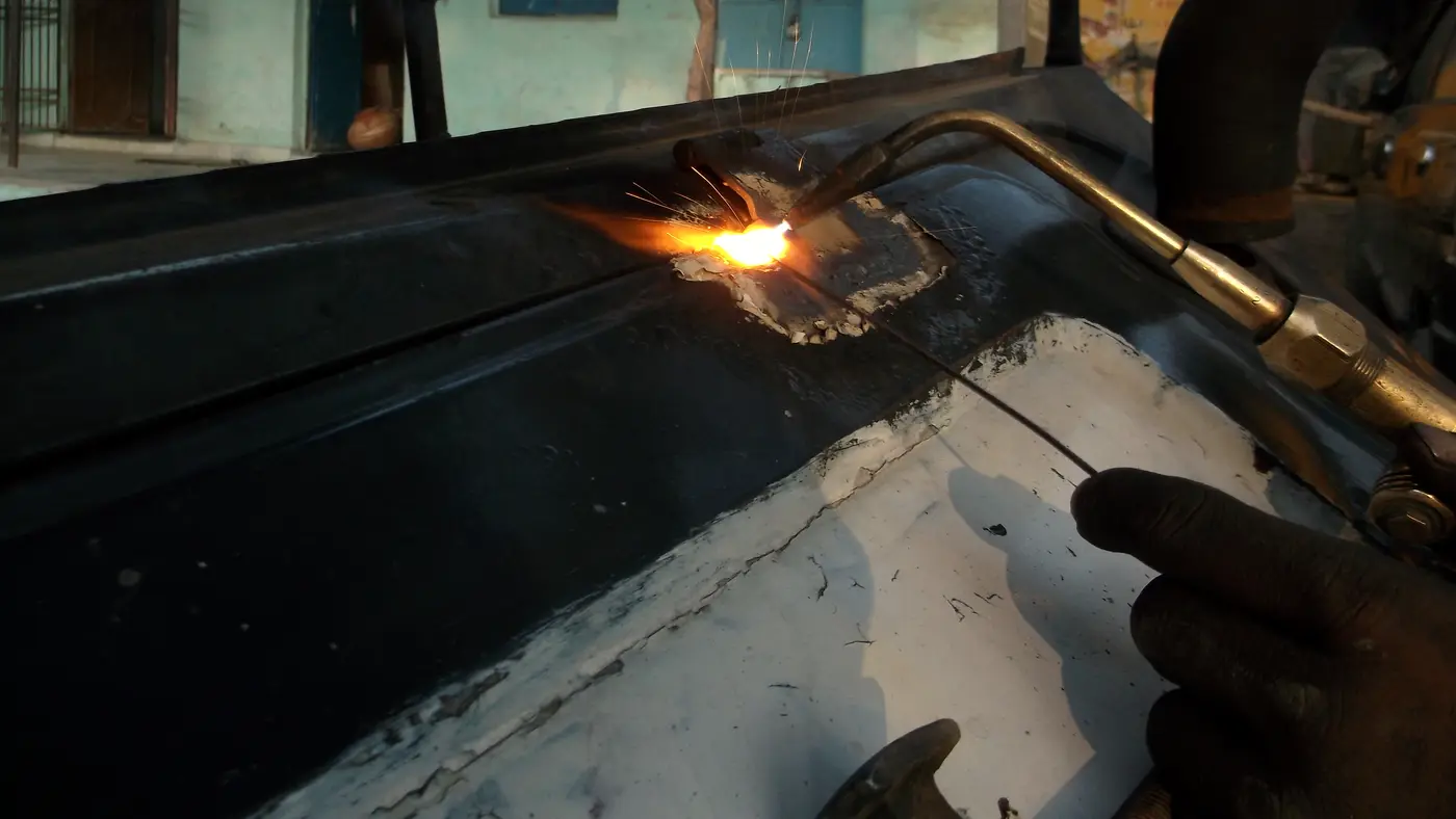 Worker cutting sheet metal with a gas torch