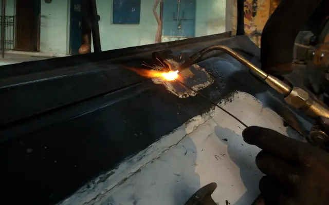 Worker cutting sheet metal with a gas torch