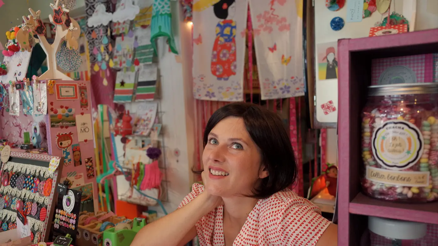Smiling shop owner leaning on the counter of her craft store