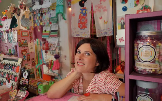 Smiling shop owner leaning on the counter of her craft store