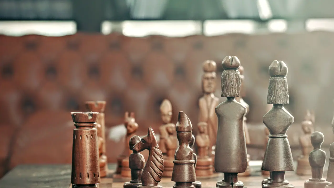 Carved wooden chess pieces on a board in a lounge