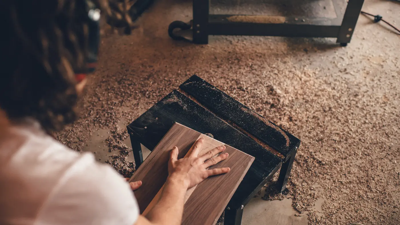 Woodworker sanding a wooden stool in a workshop