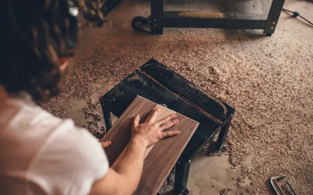 Woodworker sanding a wooden stool in a workshop