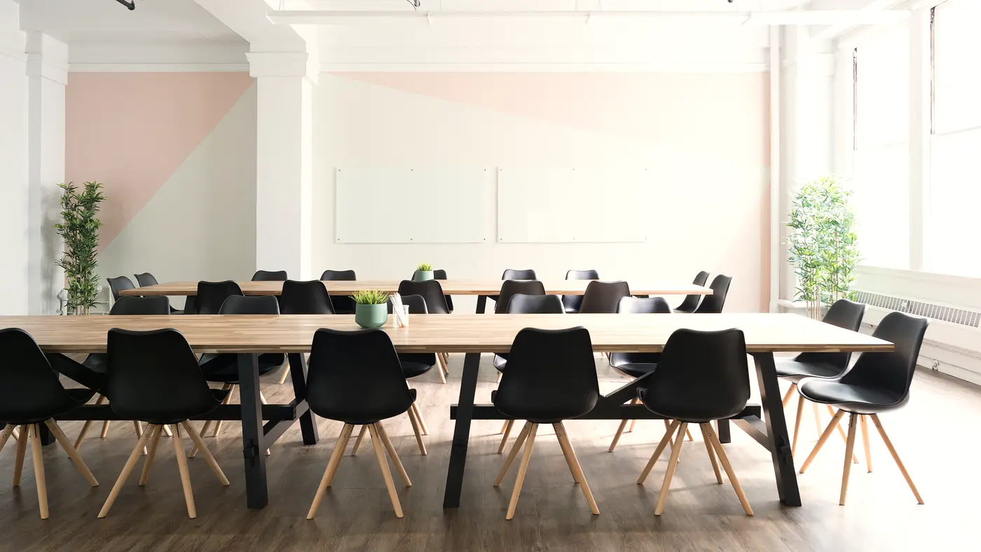Airy meeting space with a long wooden table and black chairs