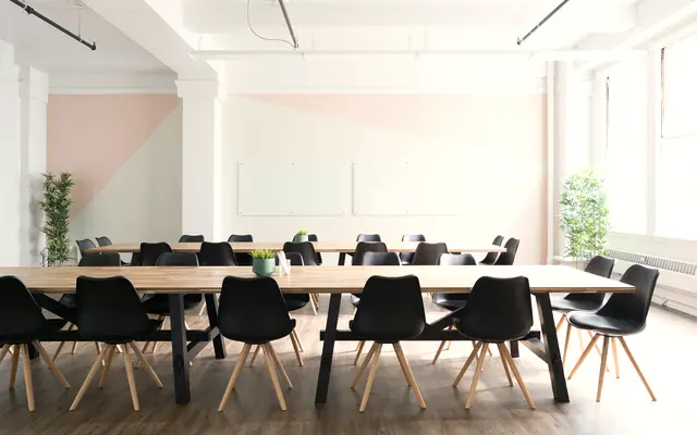 Airy meeting space with a long wooden table and black chairs