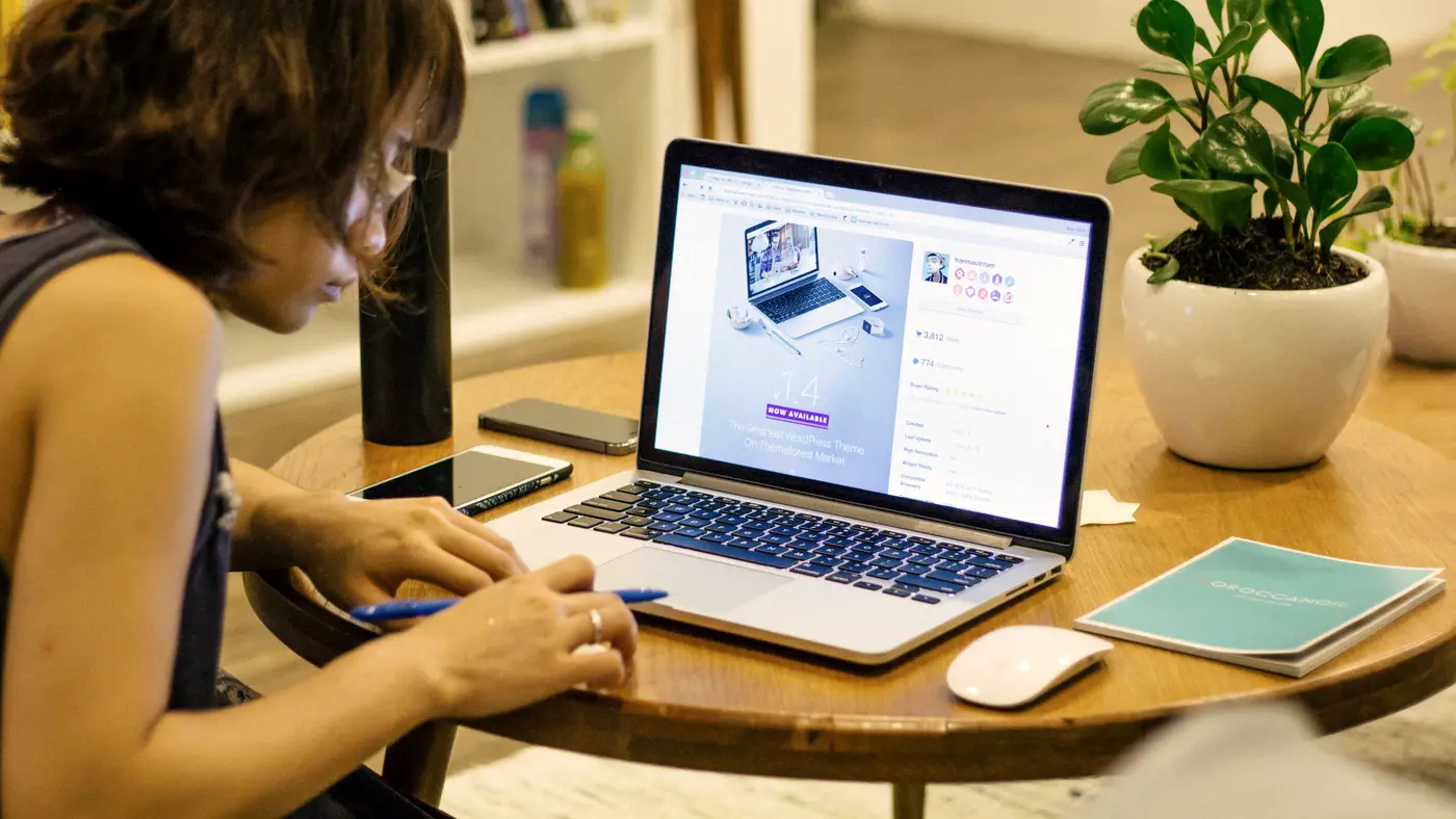Woman working on a laptop at a round wooden table
