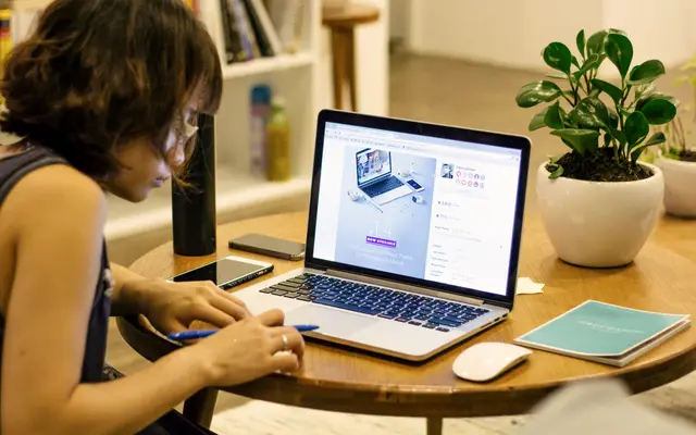 Woman working on a laptop at a round wooden table