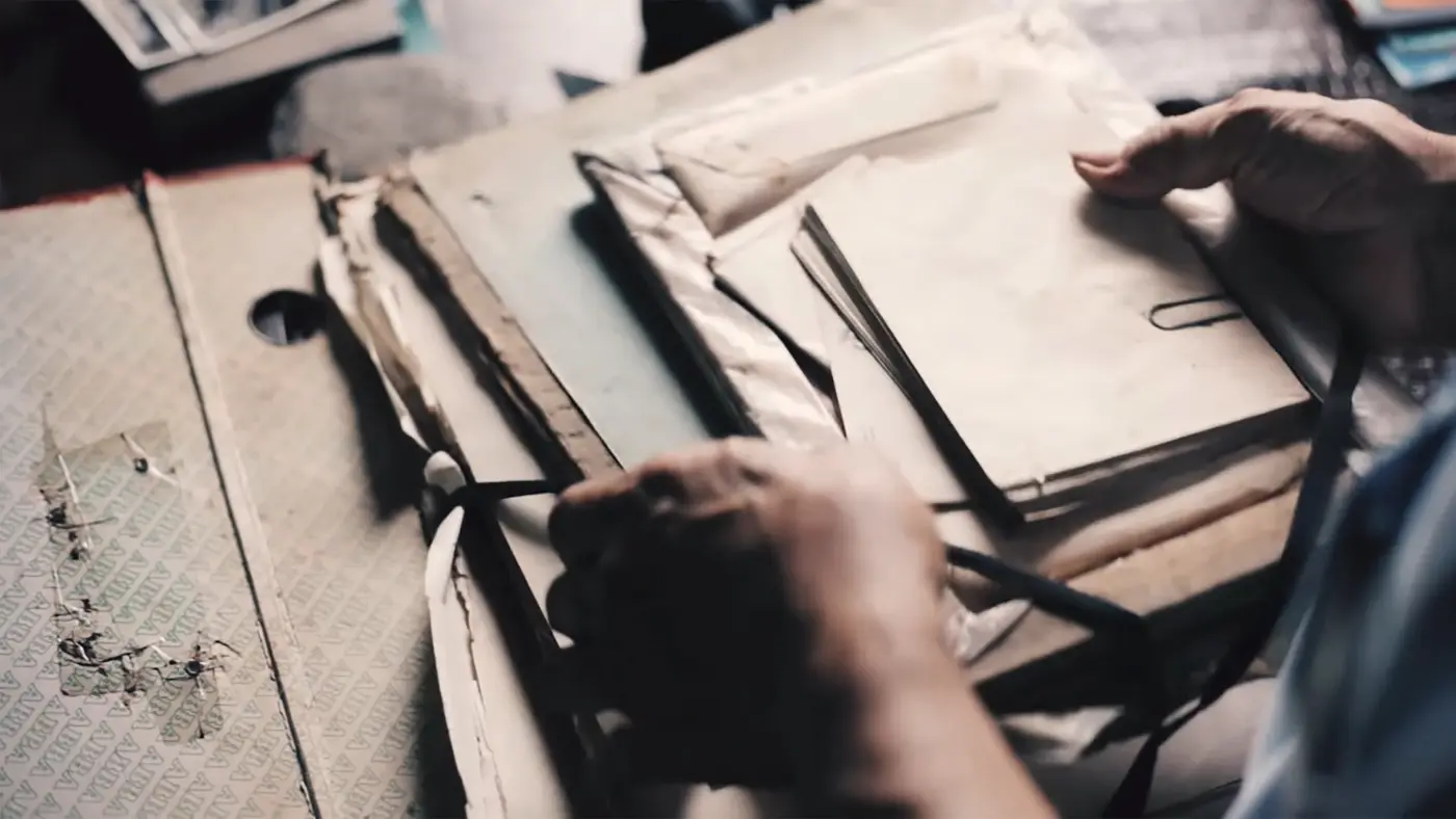 Hands sorting through old files and paper folders on a desk