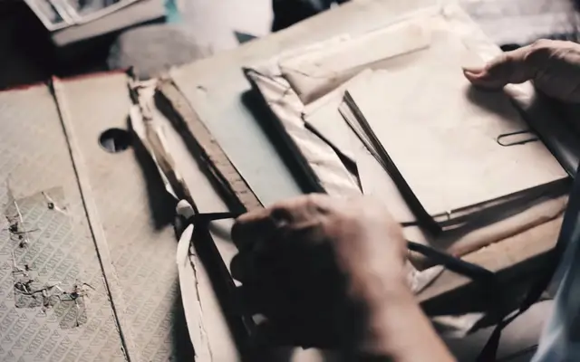 Hands sorting through old files and paper folders on a desk