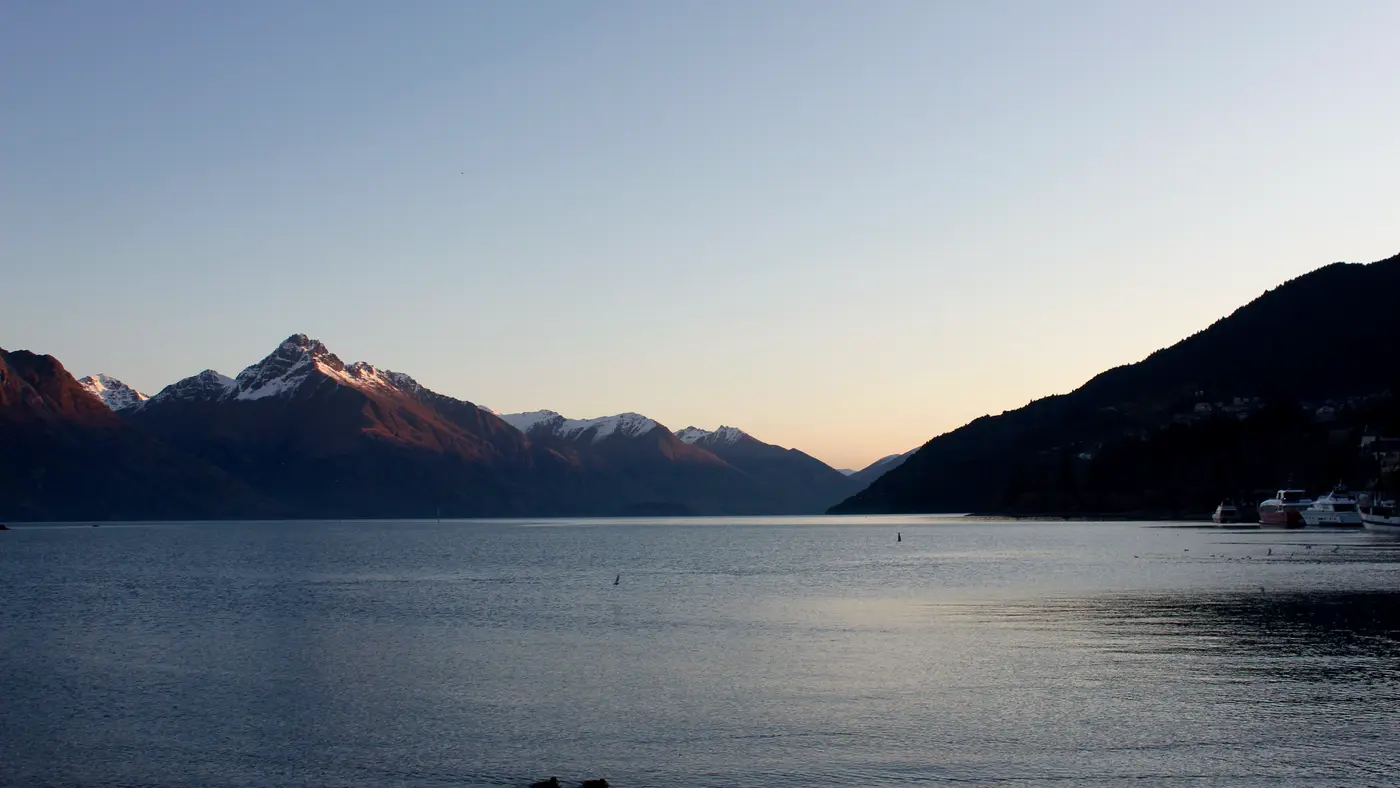 Calm lake beneath mountains in soft evening light