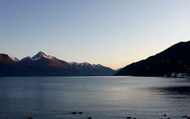 Calm lake beneath mountains in soft evening light