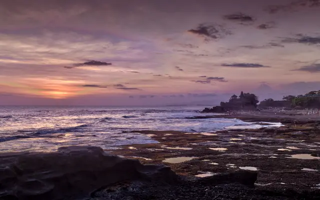 Calm purple sunset over a rocky shoreline