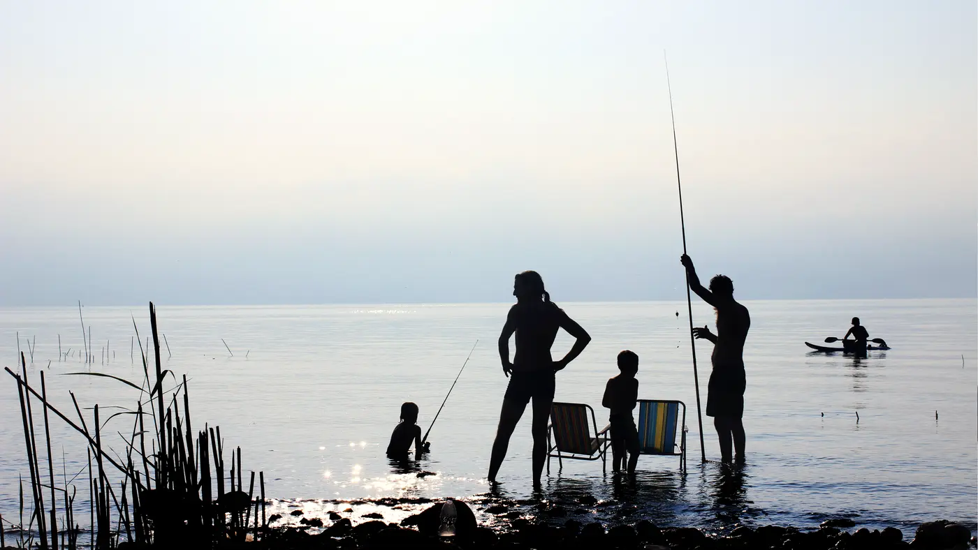 Family fishing together in a calm lake at dusk