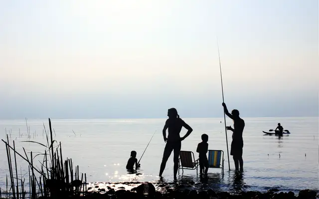 Family fishing together in a calm lake at dusk