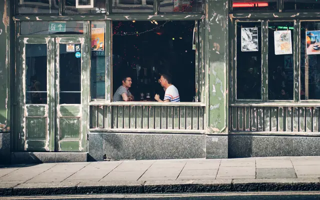 Two men chatting at the window table of a neighborhood cafe