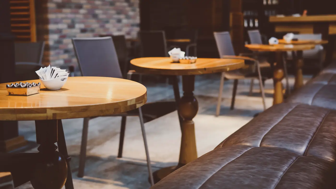 Empty cafe interior with wooden tables and a leather bench