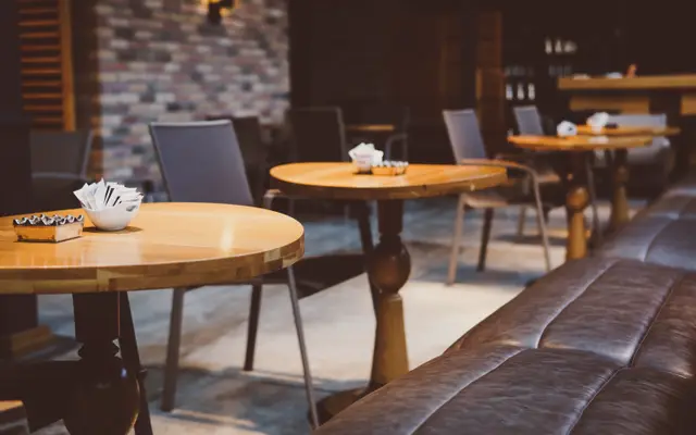Empty cafe interior with wooden tables and a leather bench