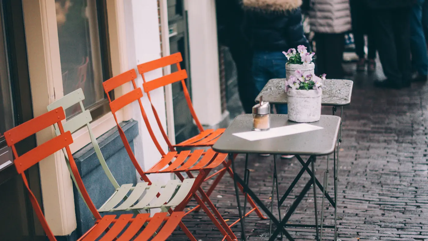 Orange bistro chairs and small tables outside a cafe
