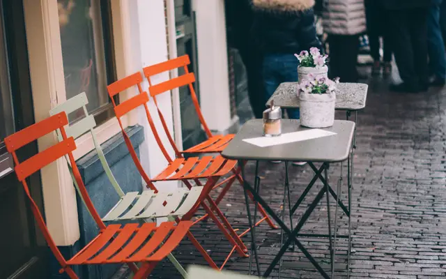 Orange bistro chairs and small tables outside a cafe