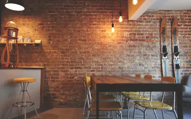 Empty cafe interior with brick wall, wooden table and stools
