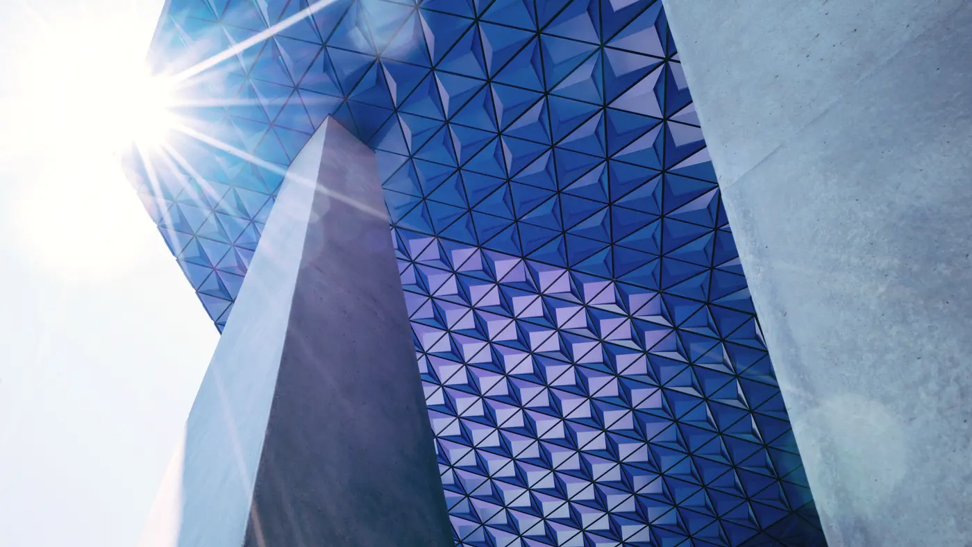 Faceted blue glass building catching bright sunlight from below