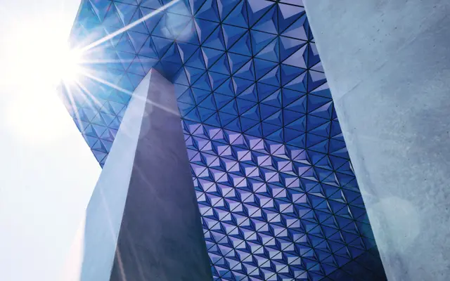 Faceted blue glass building catching bright sunlight from below
