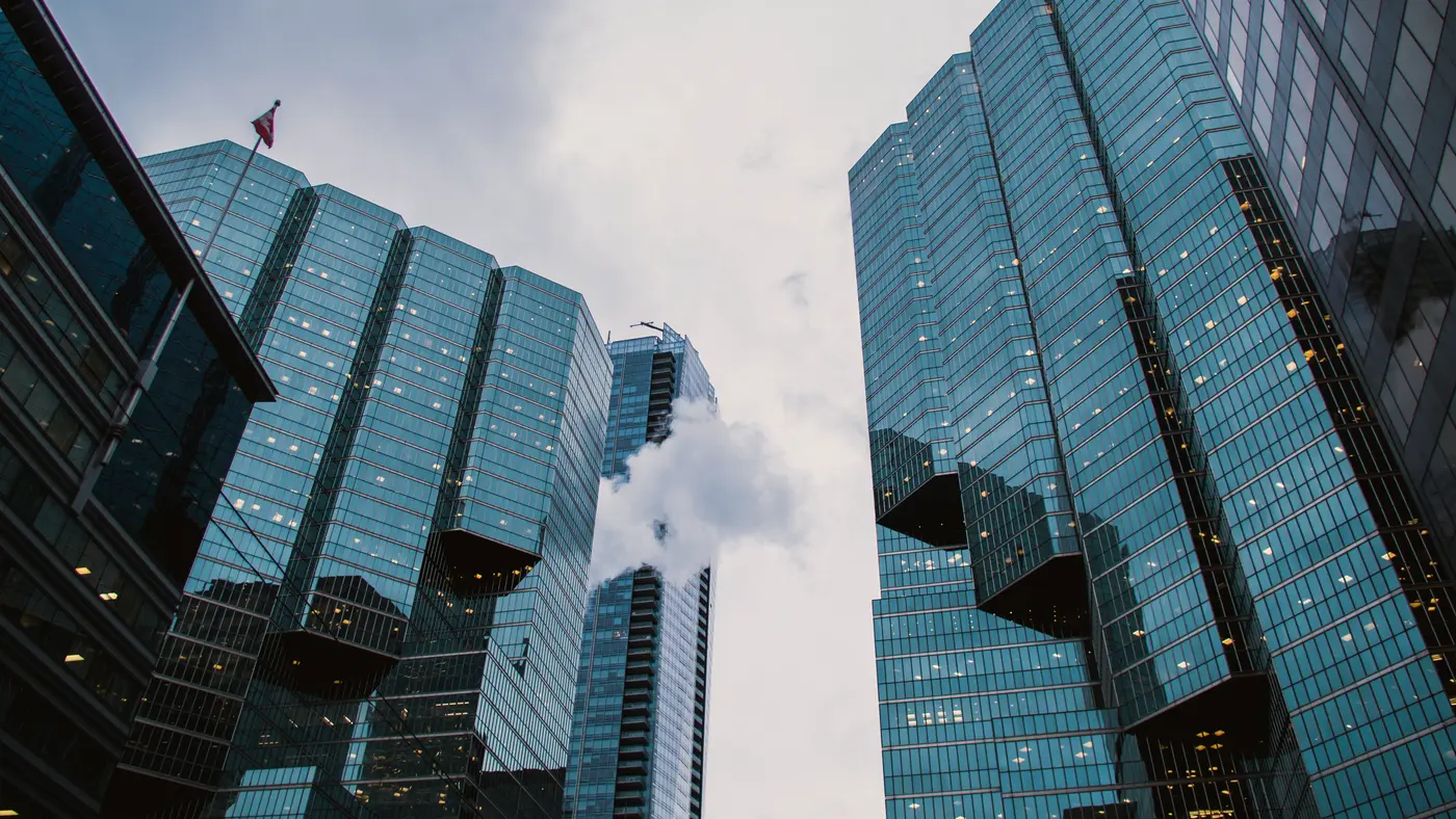 Glass office towers seen from street level under cloudy sky