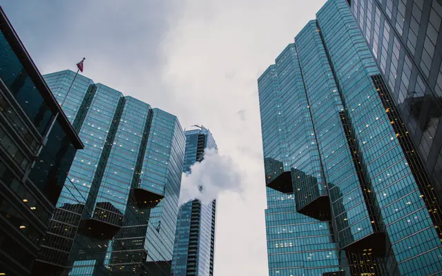 Glass office towers seen from street level under cloudy sky