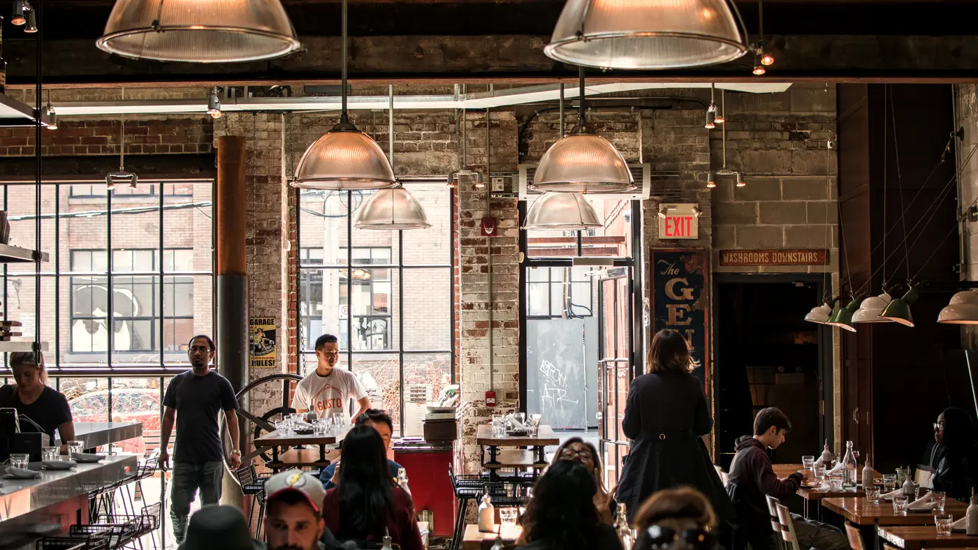Busy neighbourhood restaurant with diners under industrial pendant lights
