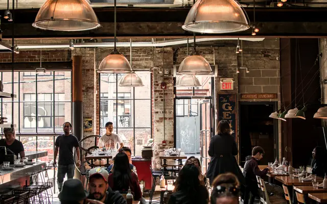 Busy neighbourhood restaurant with diners under industrial pendant lights