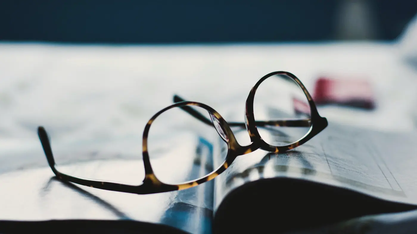 Reading glasses resting on printed papers on a desk
