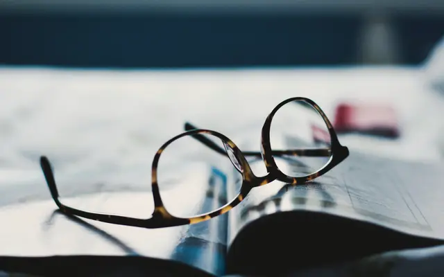 Reading glasses resting on printed papers on a desk