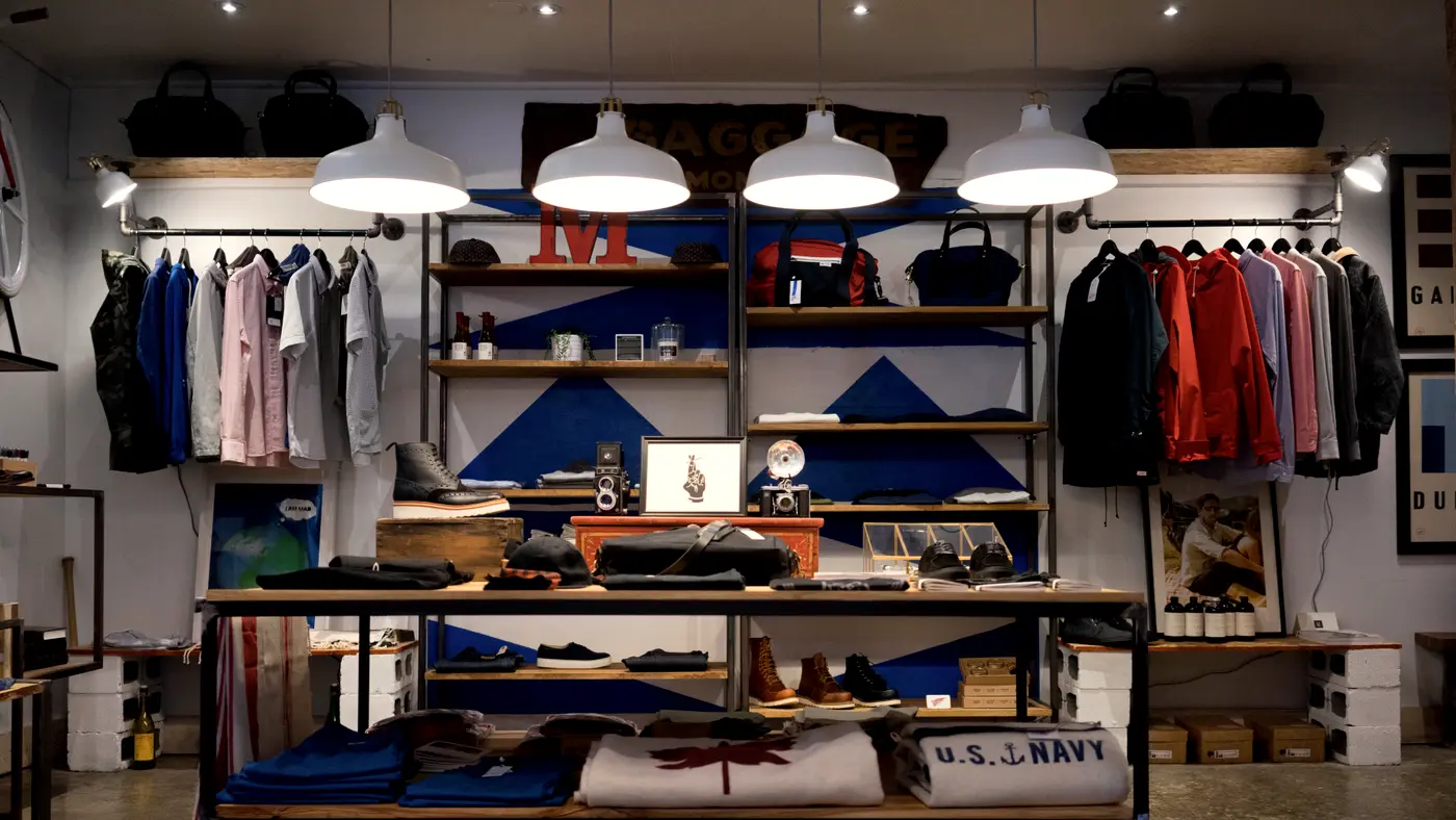 Interior of a small clothing boutique with shelves and hanging racks