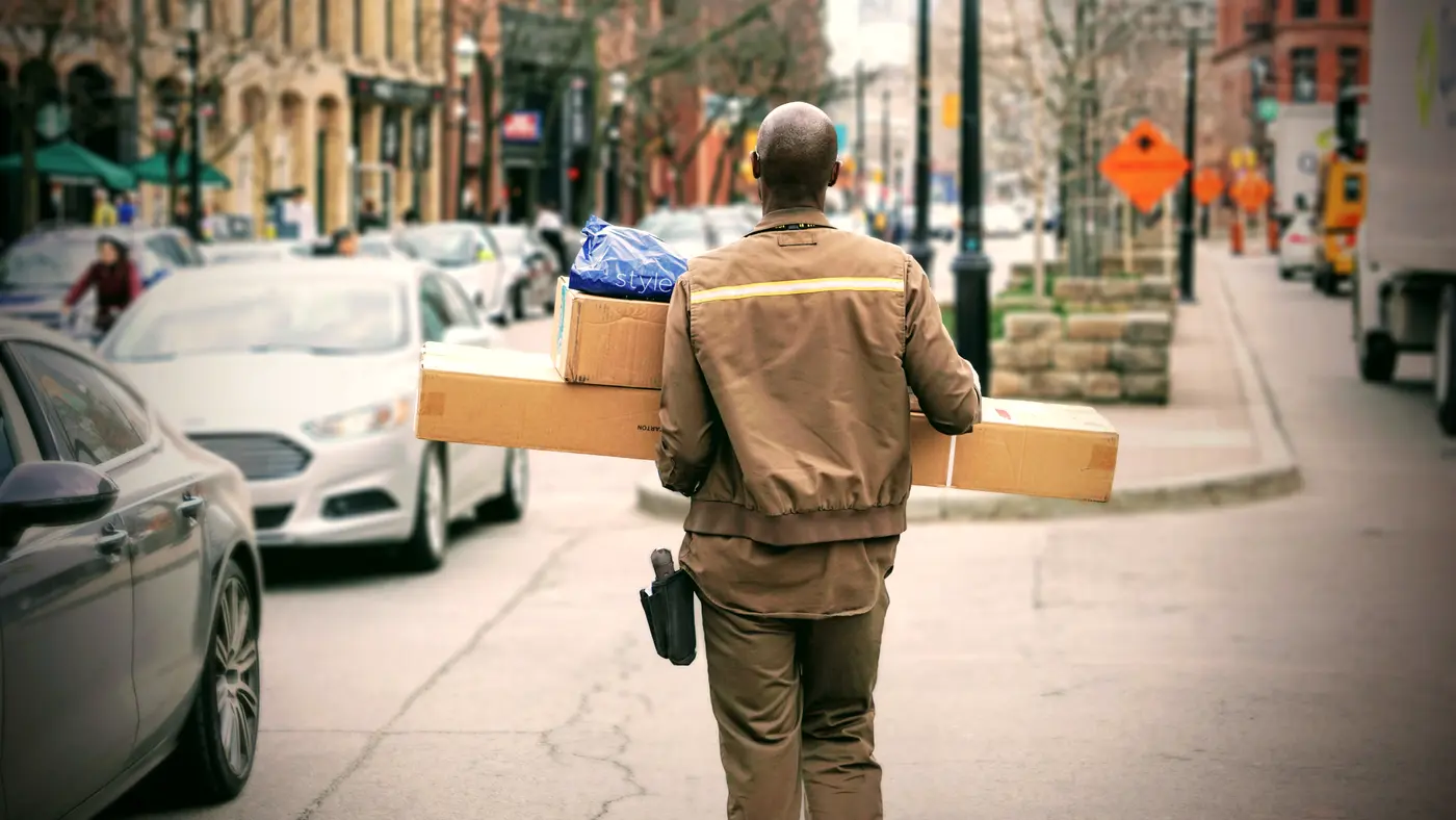 Courier carrying parcels along a busy downtown sidewalk
