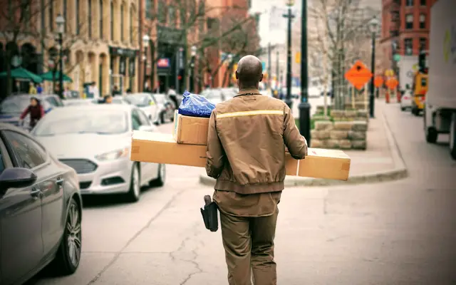 Courier carrying parcels along a busy downtown sidewalk