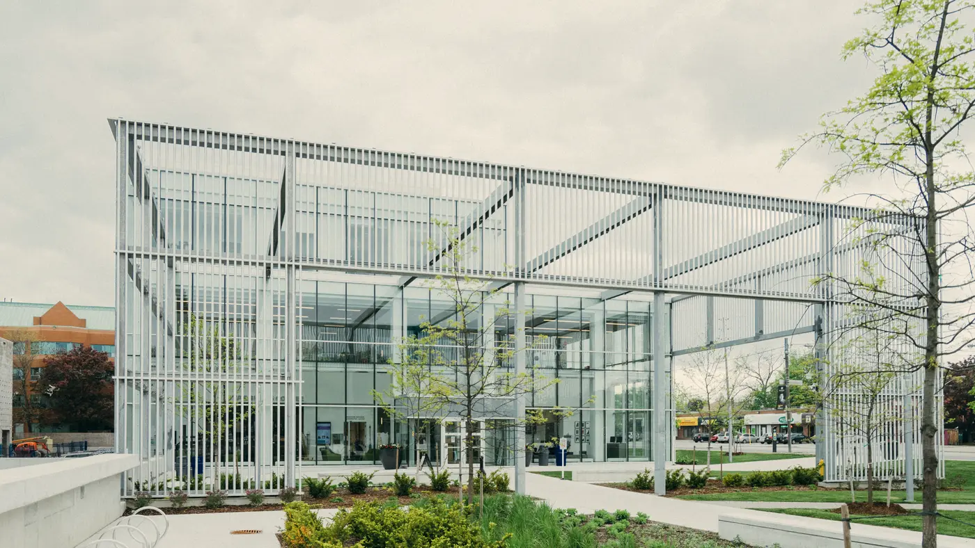 Modern glass pavilion building surrounded by landscaped gardens