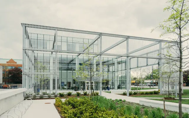 Modern glass pavilion building surrounded by landscaped gardens